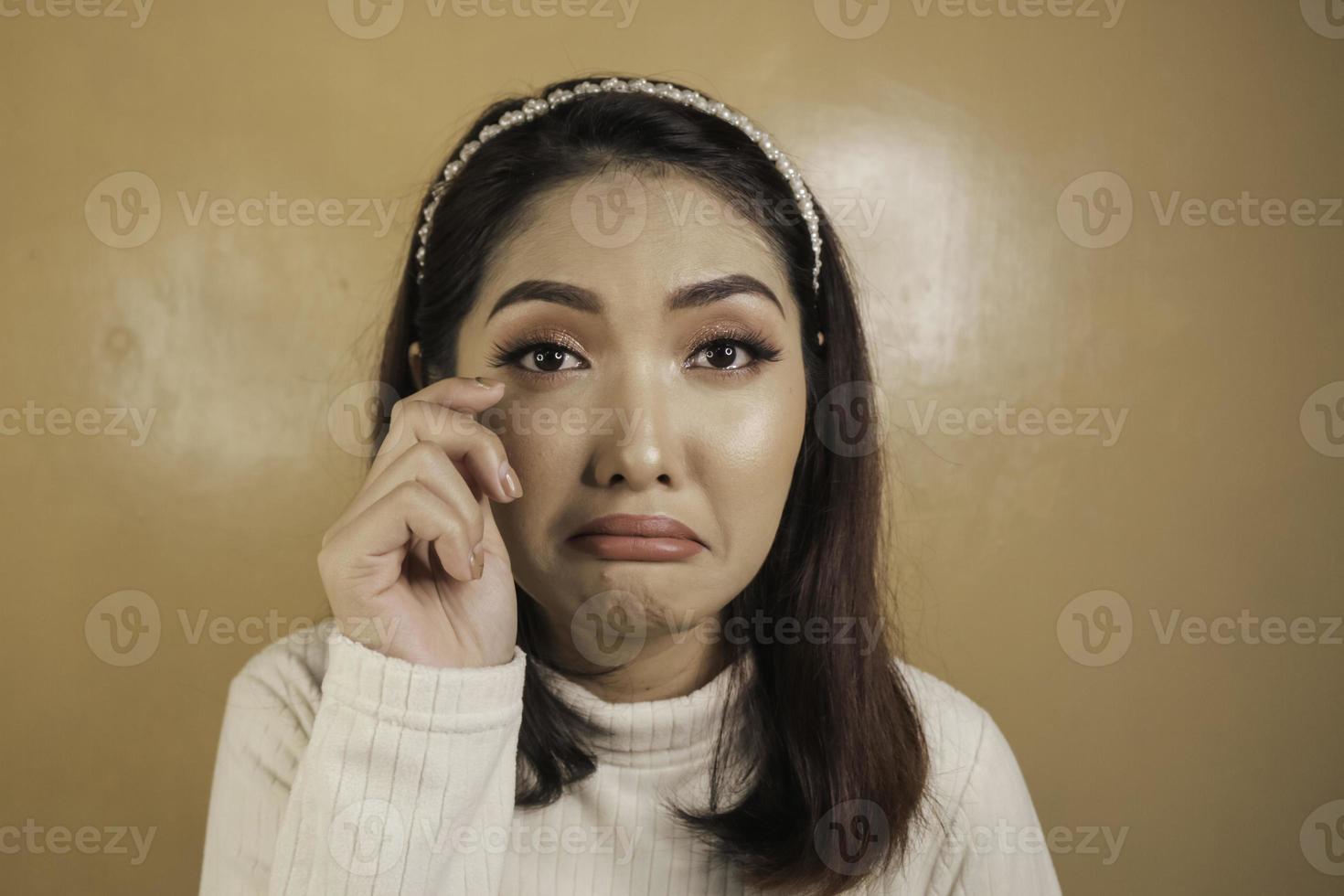 verser des larmes et triste expression d'une jeune femme asiatique en chemise blanche photo