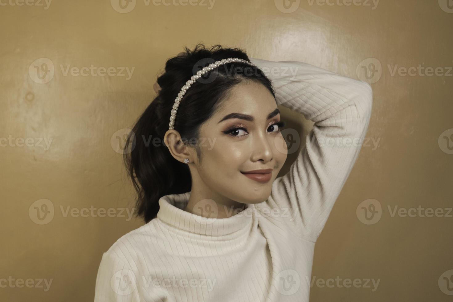 souriante jeune femme asiatique attachant ses cheveux. soin des cheveux. notion de beauté. photo