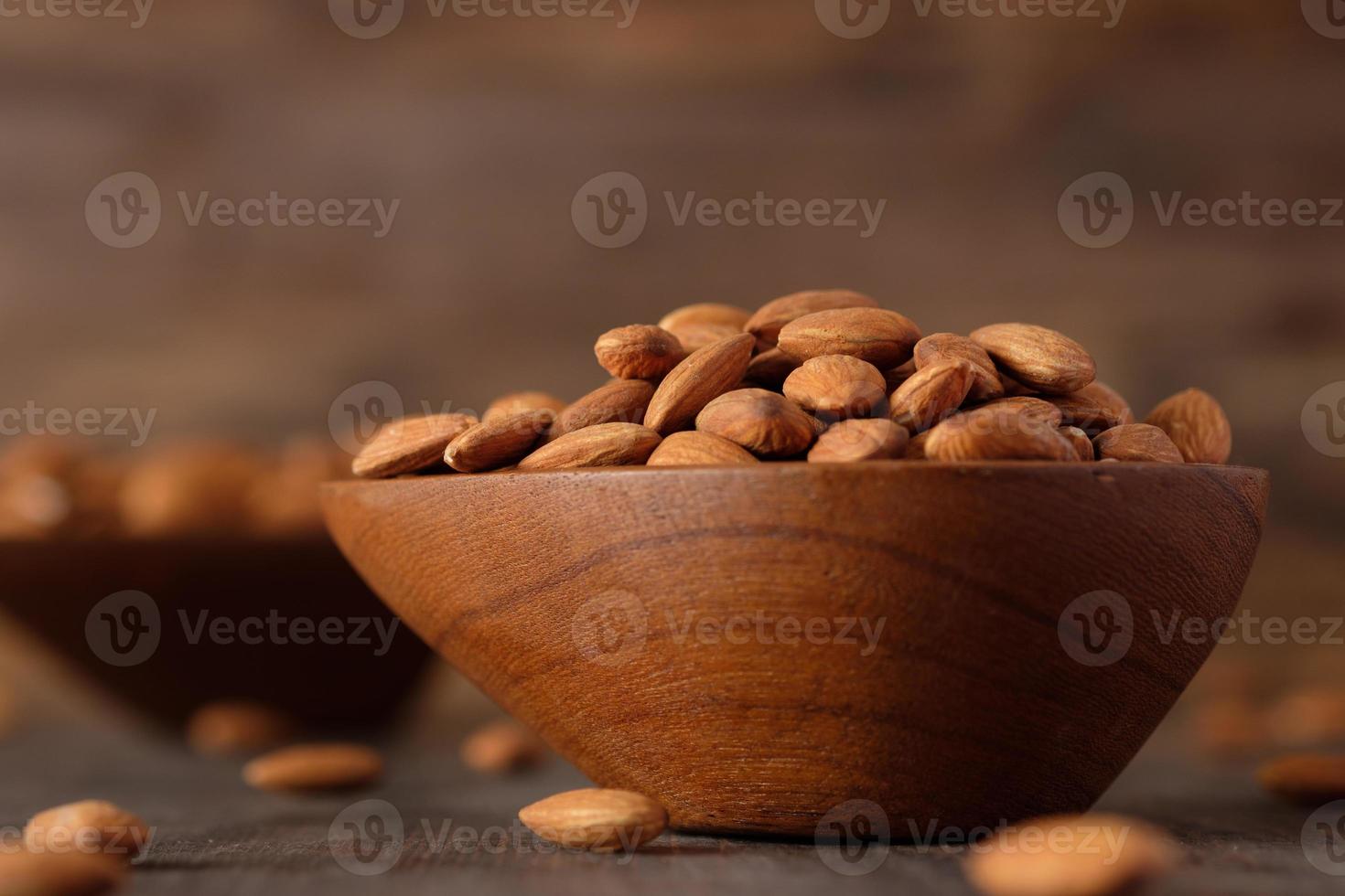 amandes dans un bol en bois sur une table en bois.matière première diététique photo