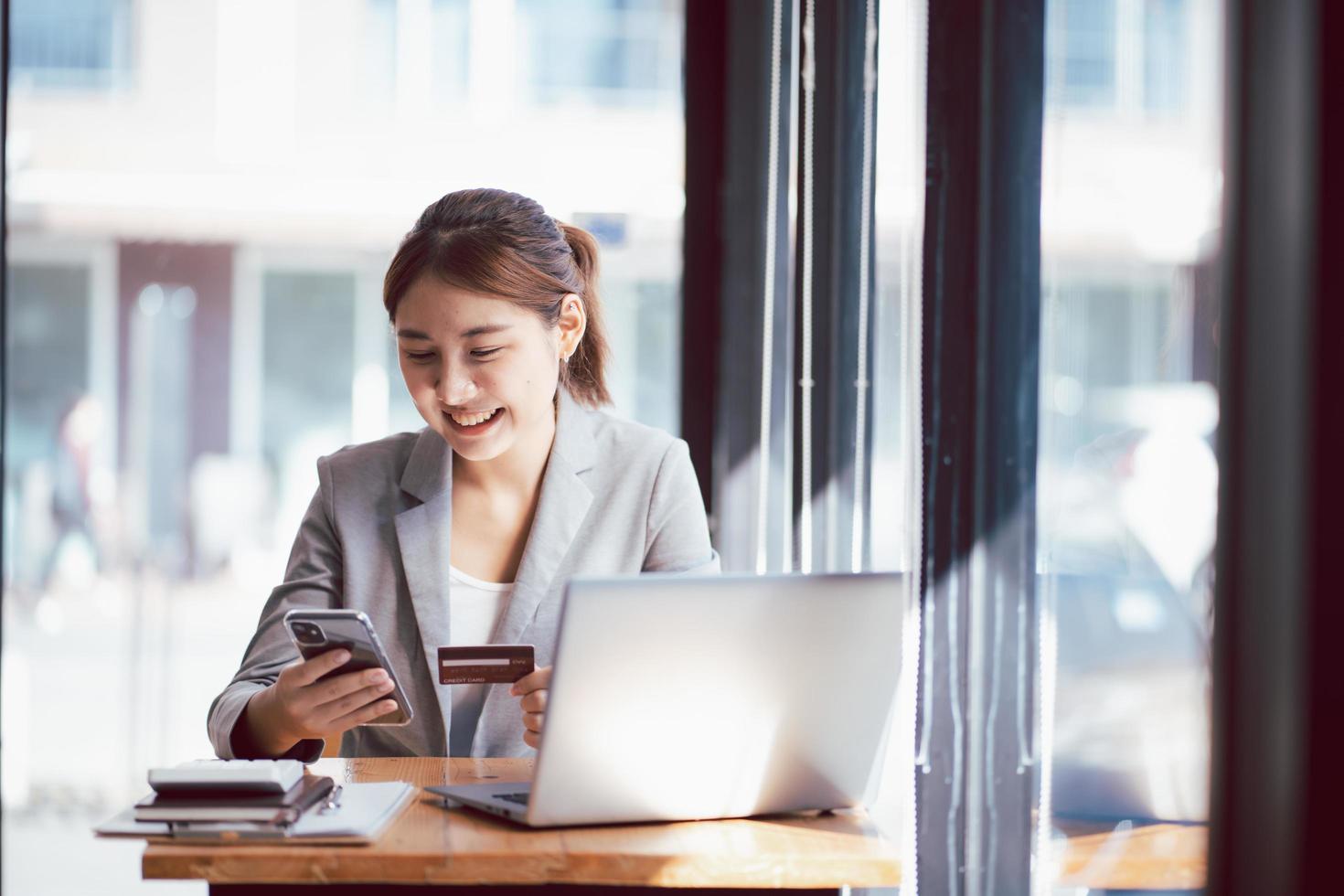 femme asiatique faisant du shopping sur internet effectuant une transaction de paiement instantanée à l'ordinateur à l'aide d'une carte de crédit. photo