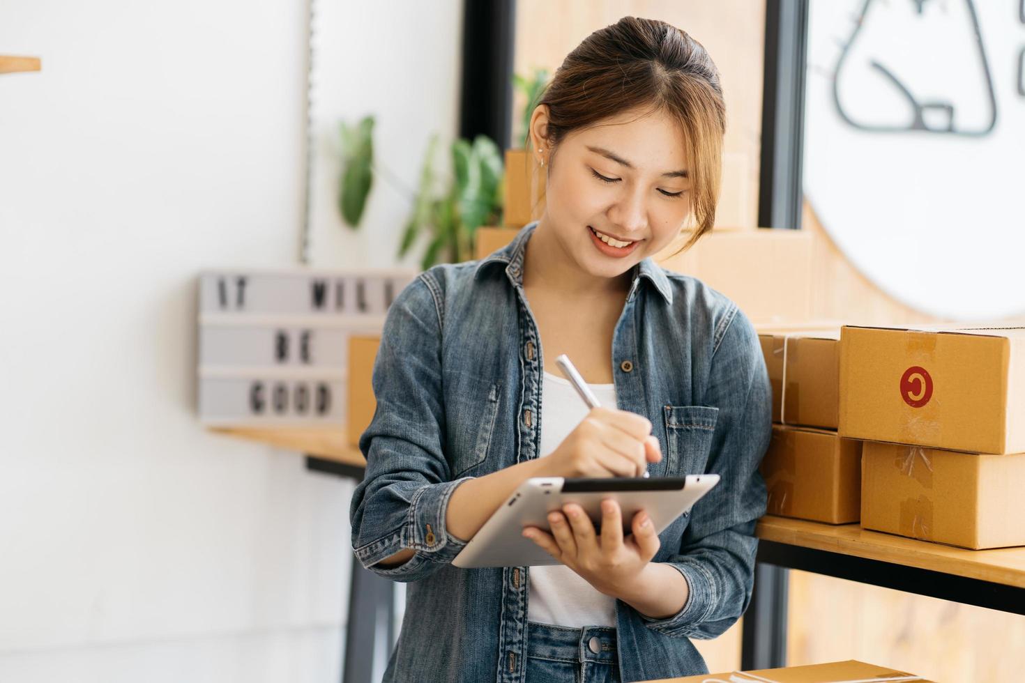 femme emballant un article qu'elle vend en ligne. jeune propriétaire de petite entreprise en démarrage emballant une boîte en carton sur le lieu de travail. une vendeuse indépendante prépare une boîte de colis de produit à livrer au client. photo