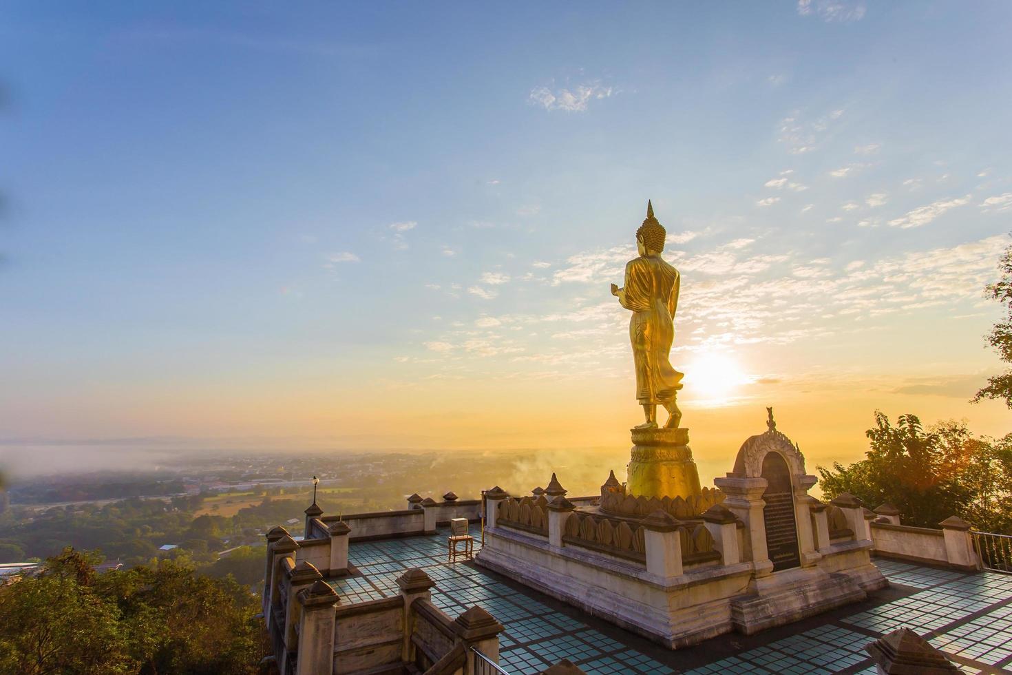 statue de bouddha doré à l'intérieur de phra ce temple khao noi le temple est situé sur la colline le matin avec du soleil et un ciel lumineux, c'est une attraction touristique majeure de nan, en thaïlande. photo