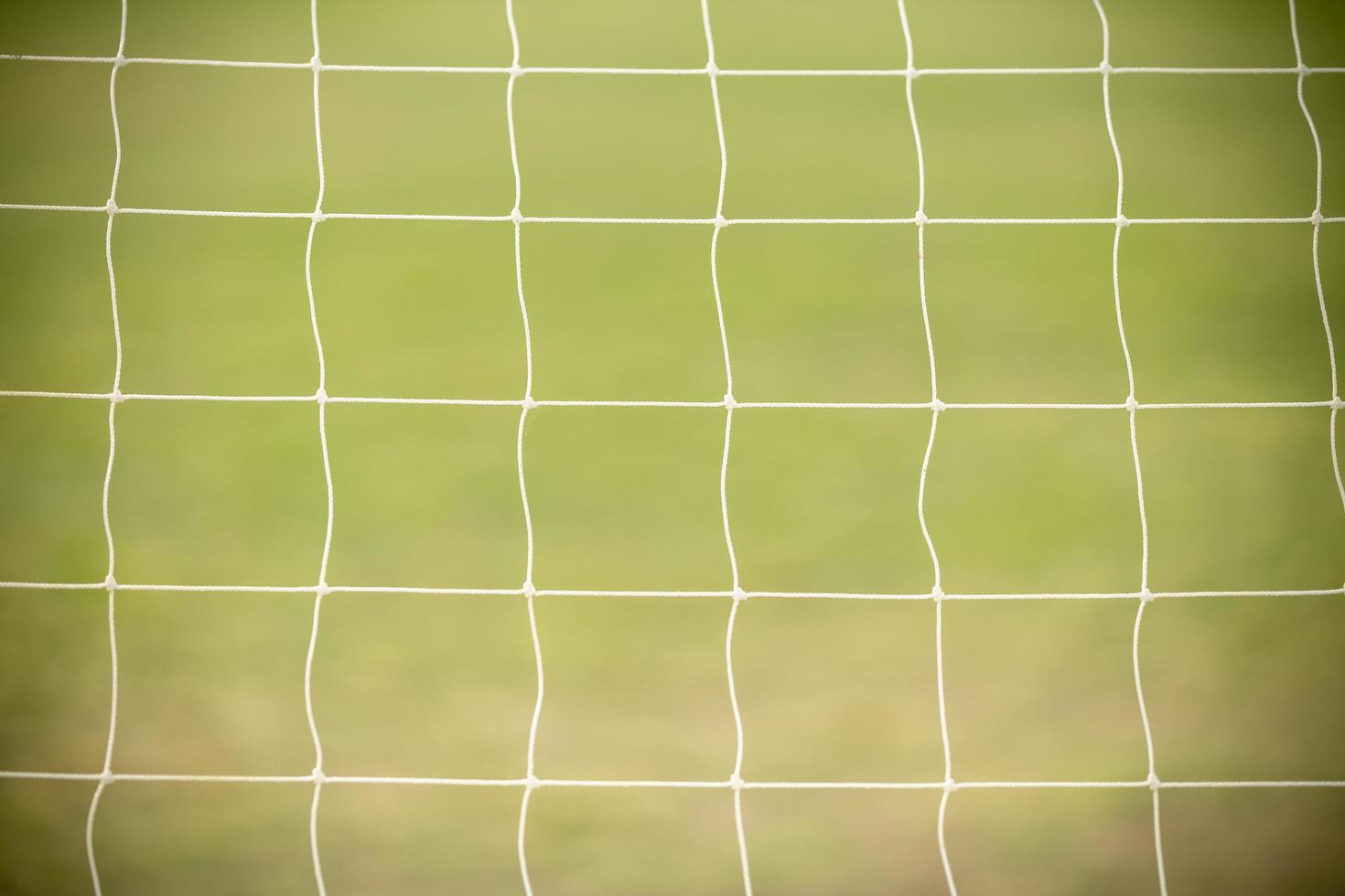 gros plan sur un filet de but de football de football blanc avec de l'herbe verte comme arrière-plan en utilisant comme fond d'écran ou arrière-plan de sport. photo