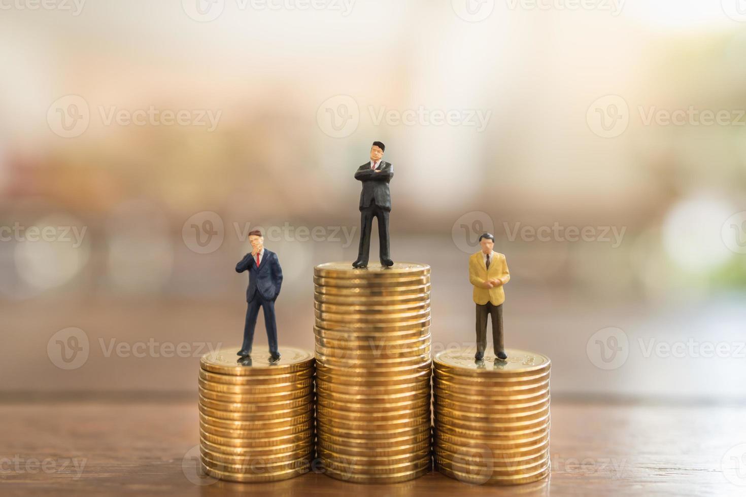 concept d'entreprise, d'investissement monétaire et de planification. gros plan d'un groupe d'hommes d'affaires miniatures figure debout sur une pile de pièces d'or sur une table en bois. photo