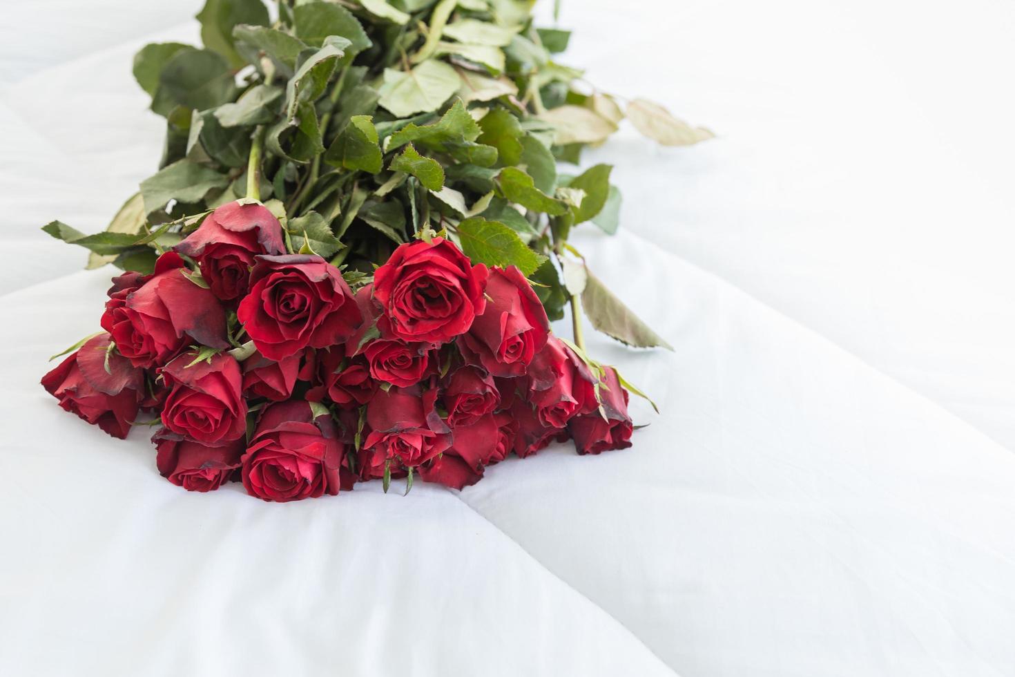 concept d'amour et de saint valentin. gros plan de bouquet de roses rouges sur un lit blanc avec espace de copie. photo