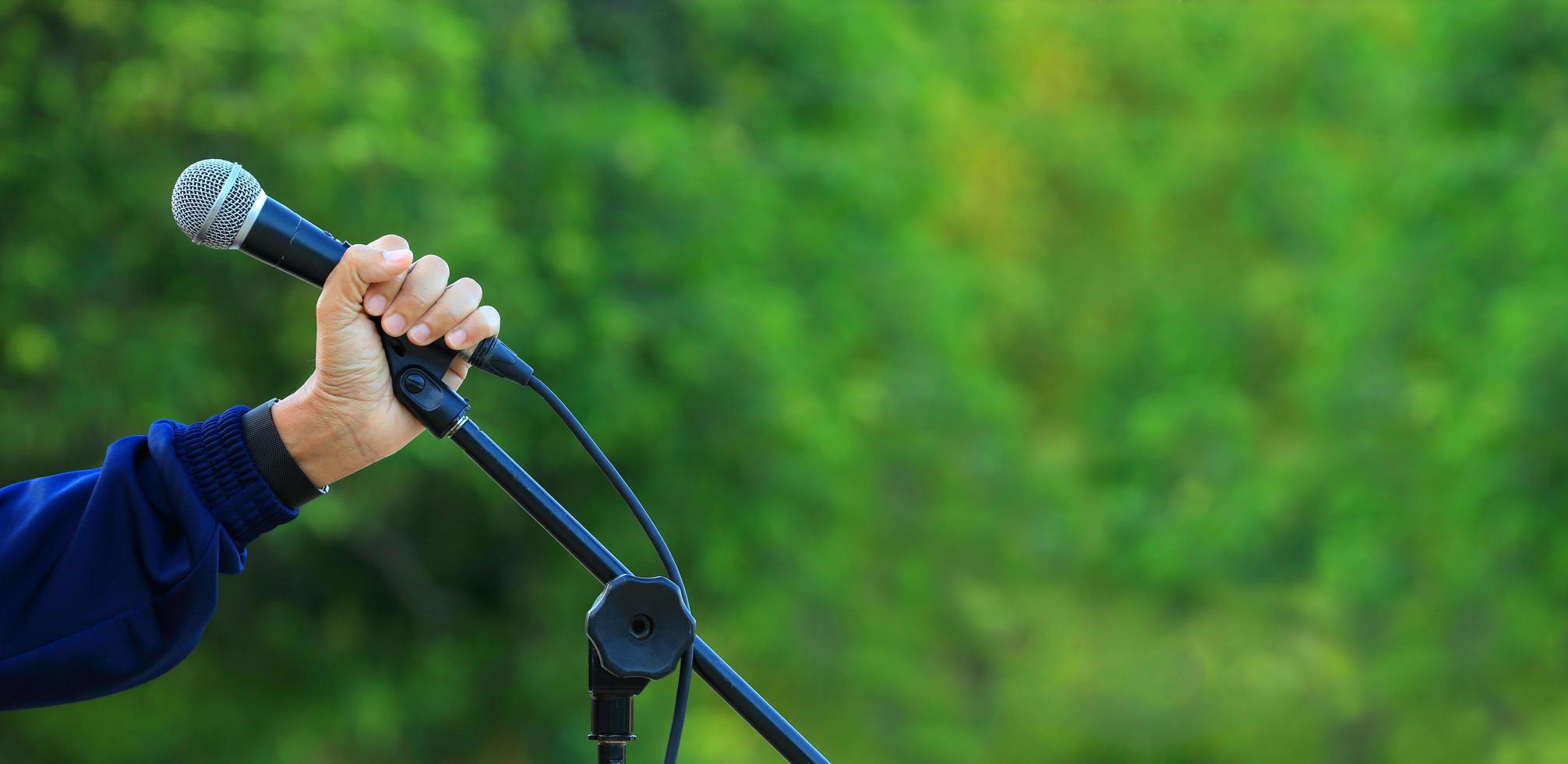 main tenant un microphone sur fond de forêt verte naturelle avec espace de copie pour la sensibilisation à l'environnement et la conception de la prise de parole en public photo