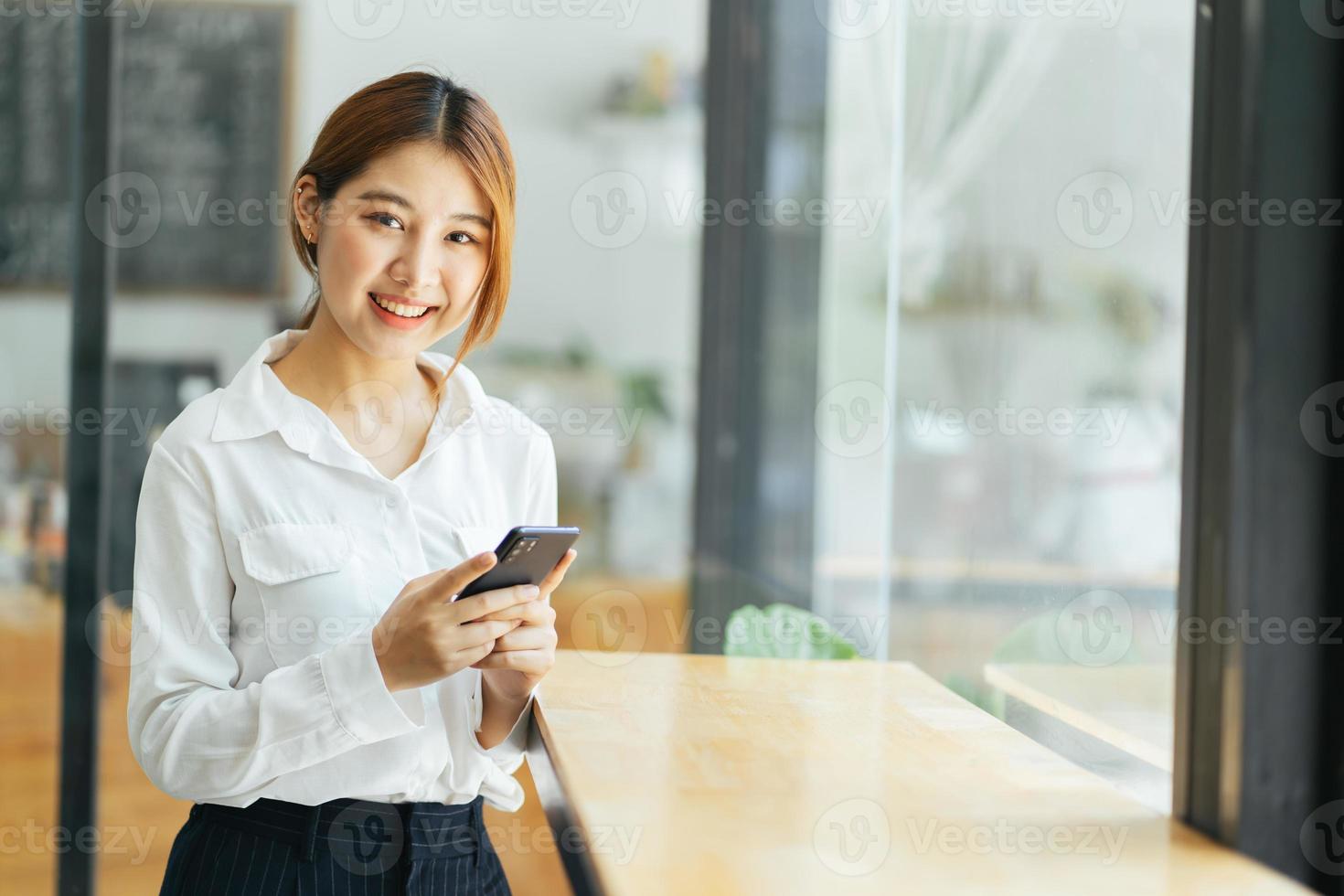 une femme d'affaires asiatique en tenue de bureau décontractée est heureuse et joyeuse tout en communiquant avec son smartphone. photo