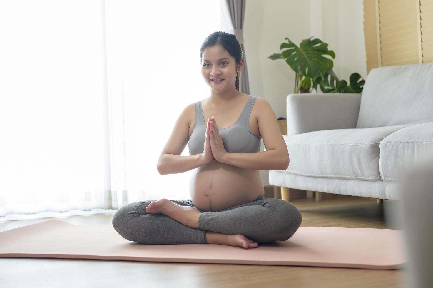 jeune femme enceinte faisant du yoga à la maison, soins de santé et concept de soins de grossesse photo