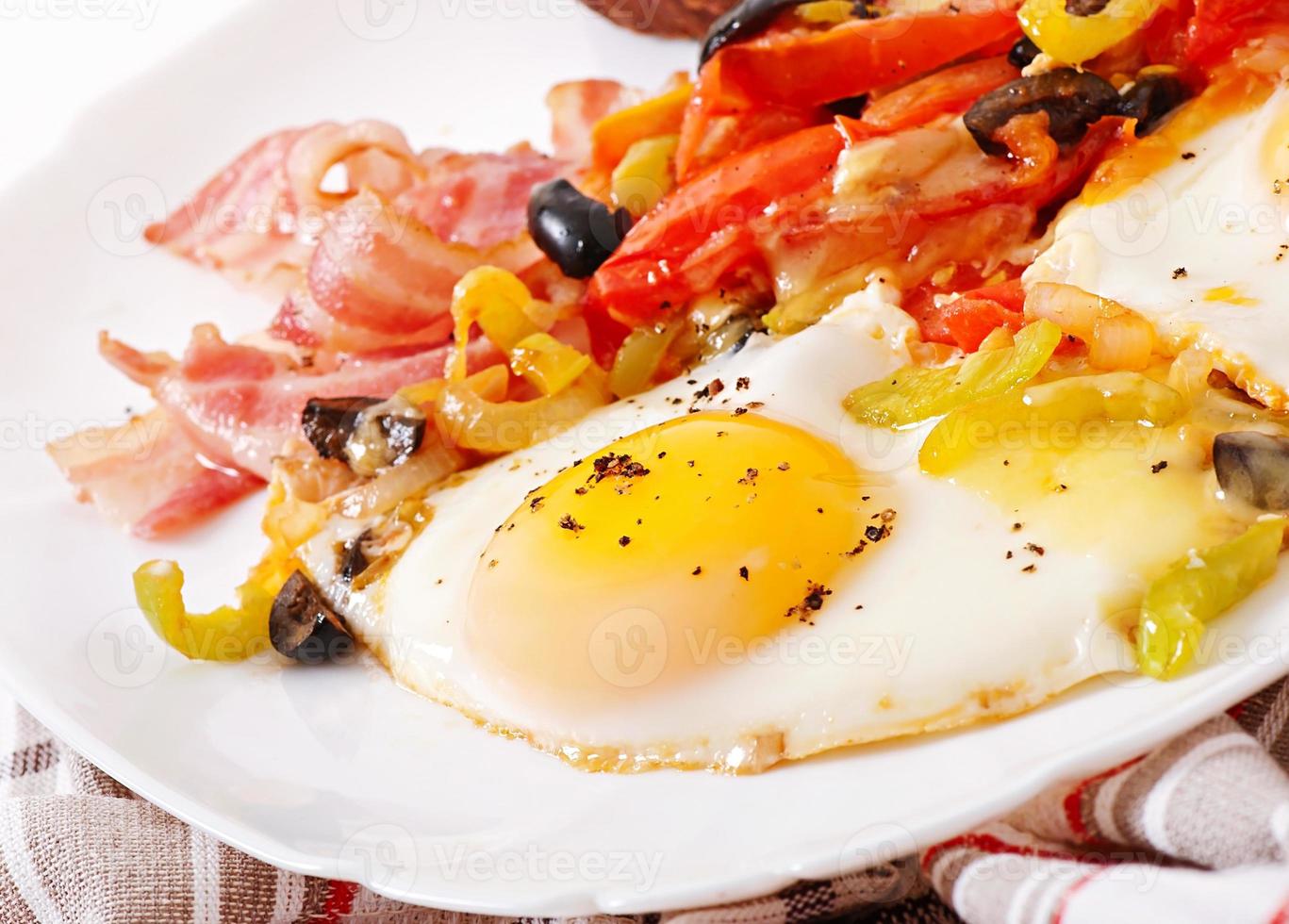 petit-déjeuner - œufs au plat avec bacon, tomates, olives et tranches de fromage photo