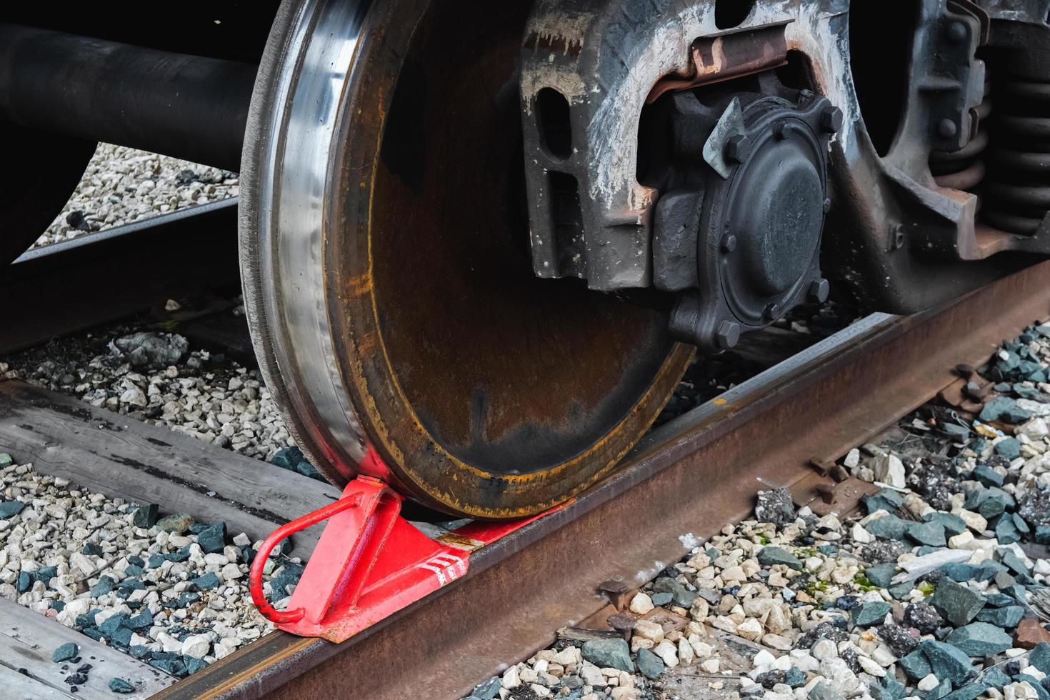 sabot rouge de frein de chemin de fer sous la roue d'un train sur rails. photo