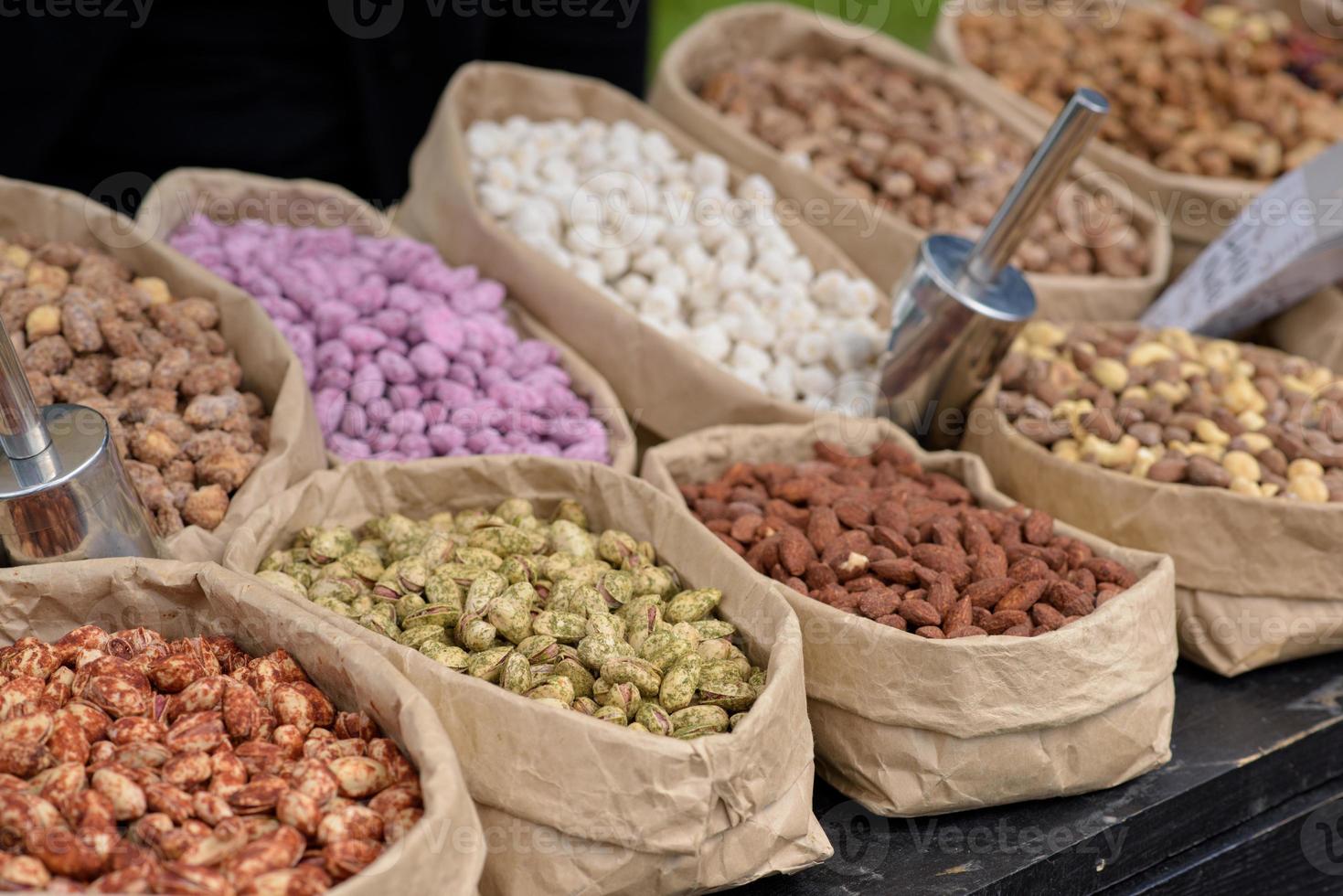 les amandes et les pistaches aux épices se trouvent dans des sacs en papier sur le comptoir. photo