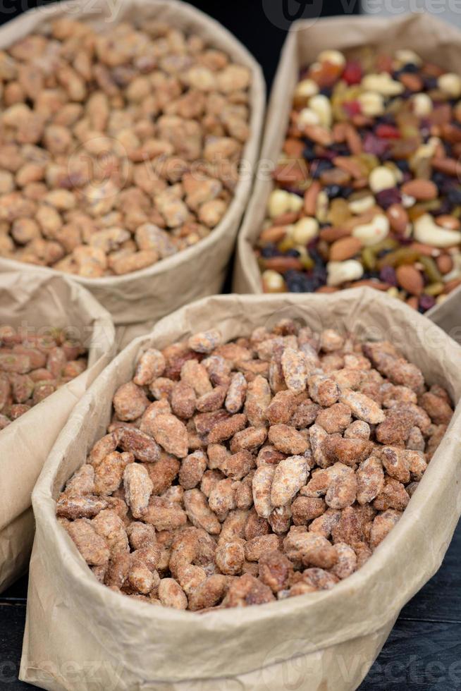 les amandes et les pistaches aux épices se trouvent dans des sacs en papier sur le comptoir. photo