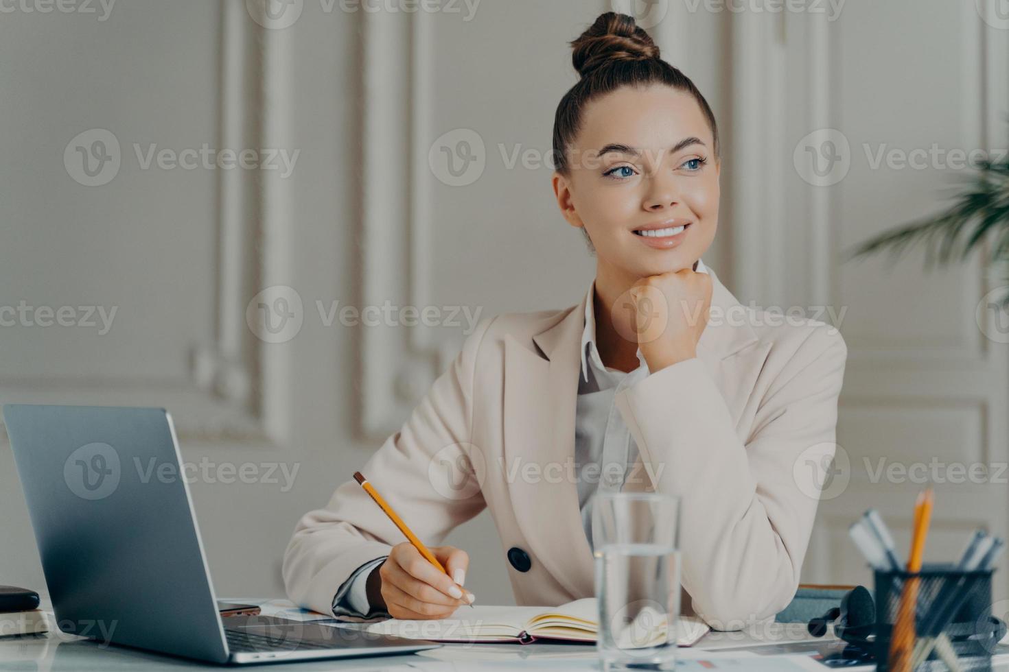 femme d'affaires heureuse en tenue classique travaillant à distance sur un ordinateur portable photo