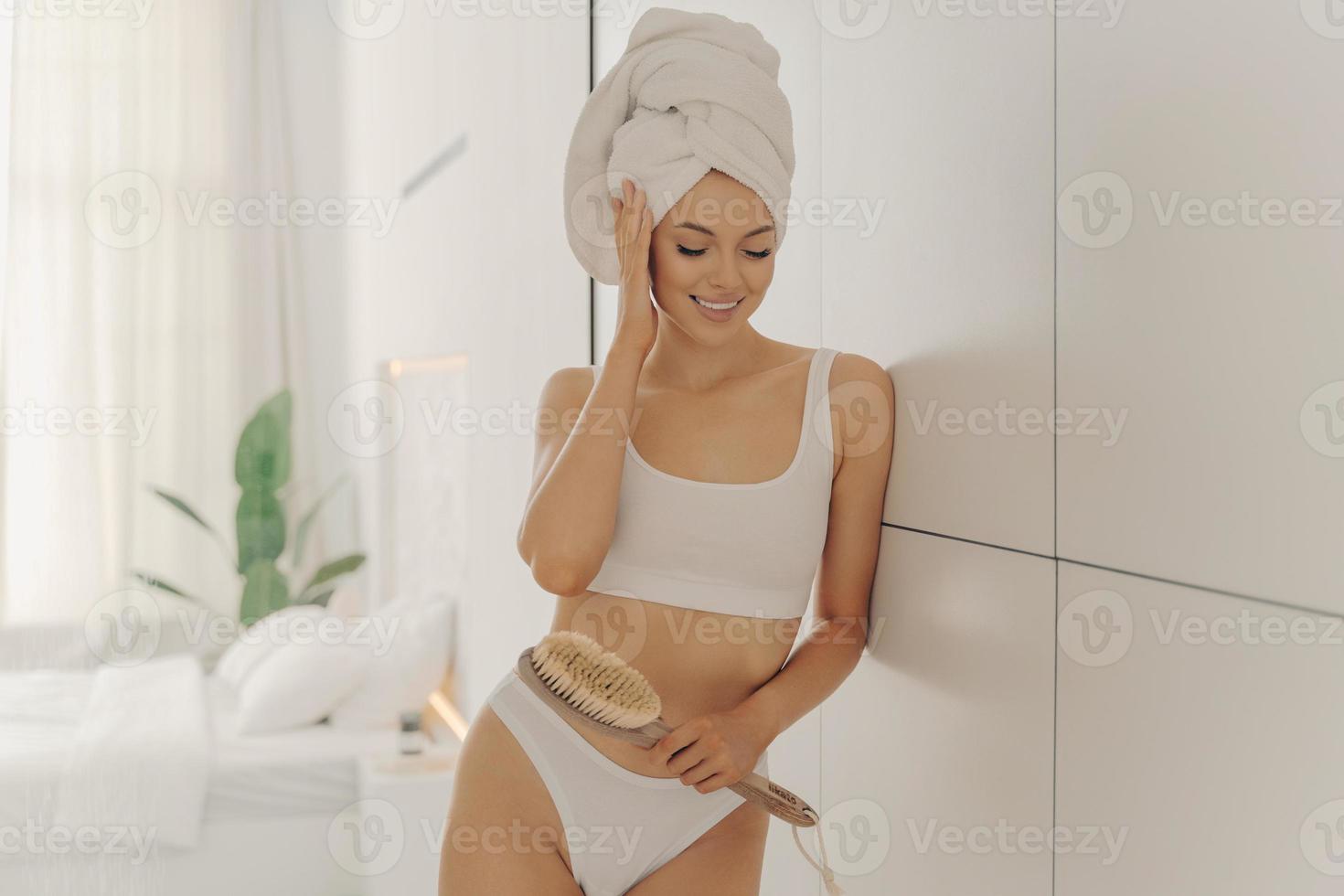 Une jeune mannequin caucasienne décontractée porte une serviette enroulée sur la tête après des soins corporels à la maison photo