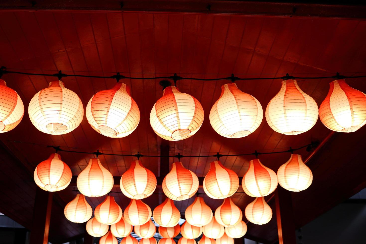 des lampes rouges tiennent sur un plafond et un éclairage en bois rouge, des rangées de lampes de style japonais. photo