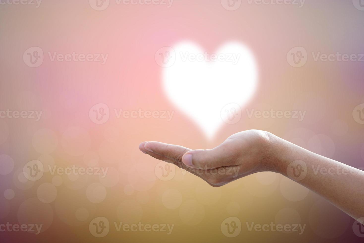 les mains bénissent le coeur dans le ciel. fond de nature floue photo