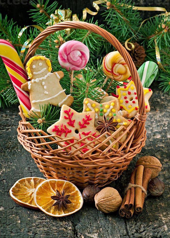 Biscuits de pain d'épice de noël et sucettes dans un panier sur fond de bois ancien photo