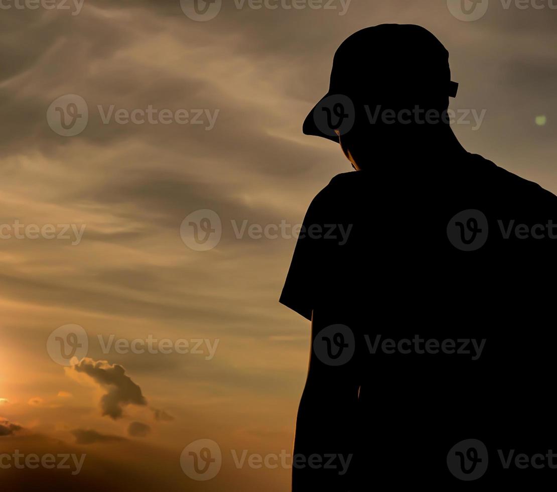 silhouette d'un homme portant un chapeau au coucher du soleil photo