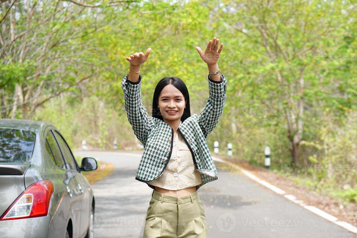 une femme asiatique appelle un mécanicien, la voiture sort sur la route autour de la forêt. photo