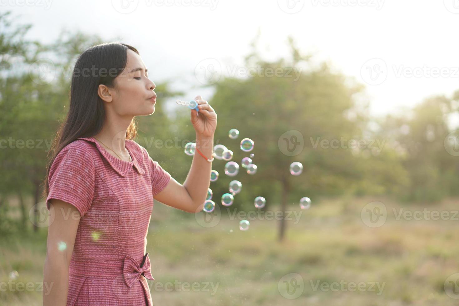 femme asiatique soufflant des bulles de savon chaque fond d'herbe verte photo