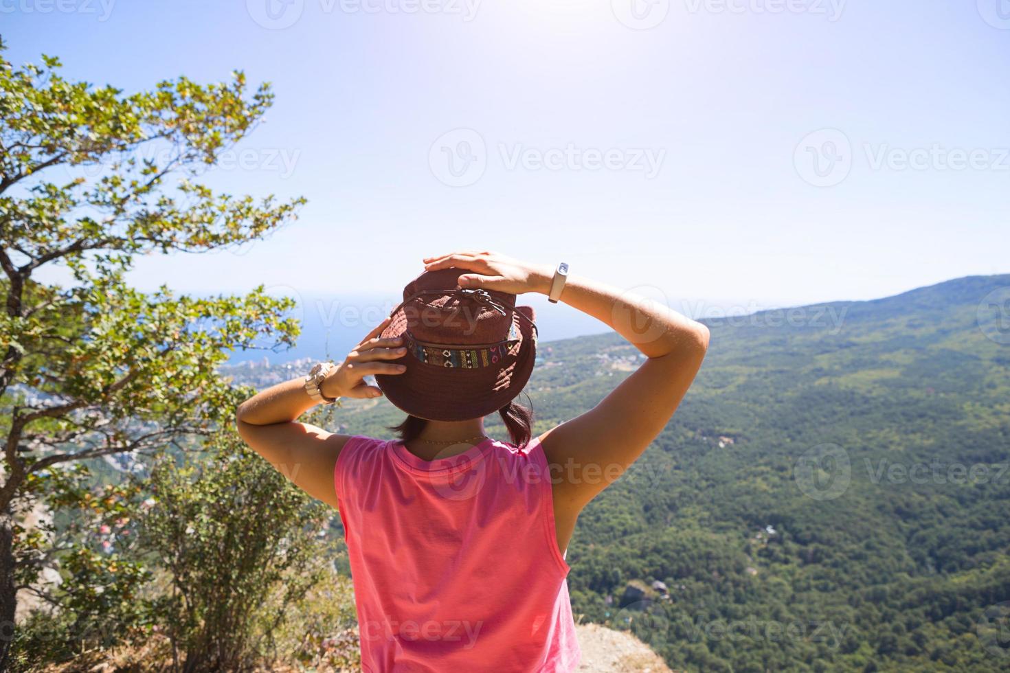 femme au chapeau regarde la vue panoramique de la montagne à la mer et à la forêt. tourisme, trekking, voyage. écotourisme actif, mode de vie sain, aventure photo