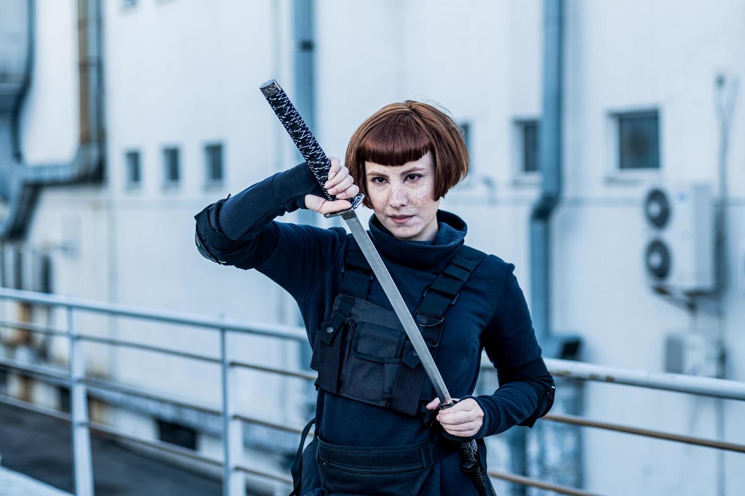 portrait d'une jeune femme rousse avec une épée japonaise vêtue d'un costume cyberpunk futuriste debout sur le toit. photo