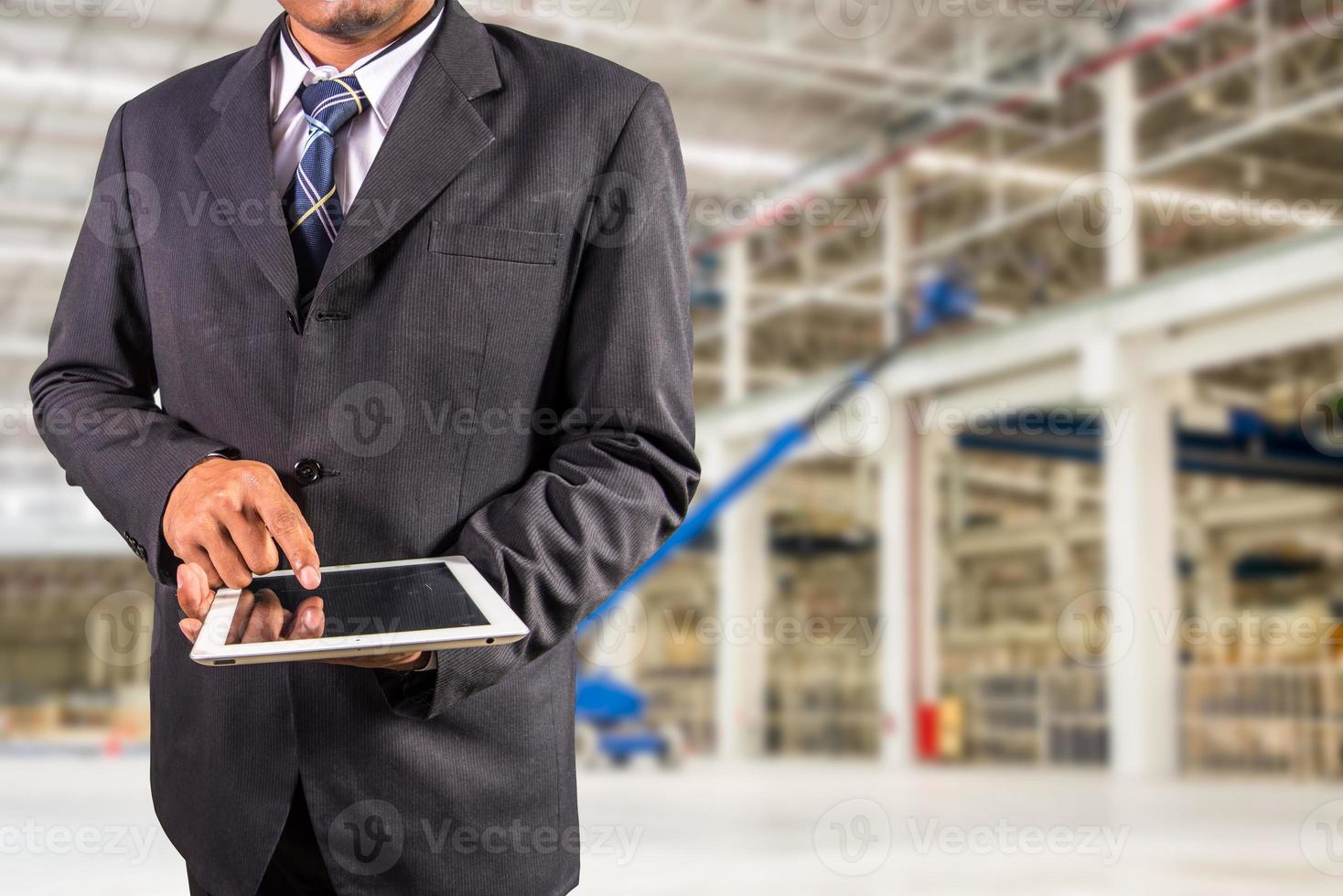 homme d'affaires tient une tablette avec fond d'usine photo