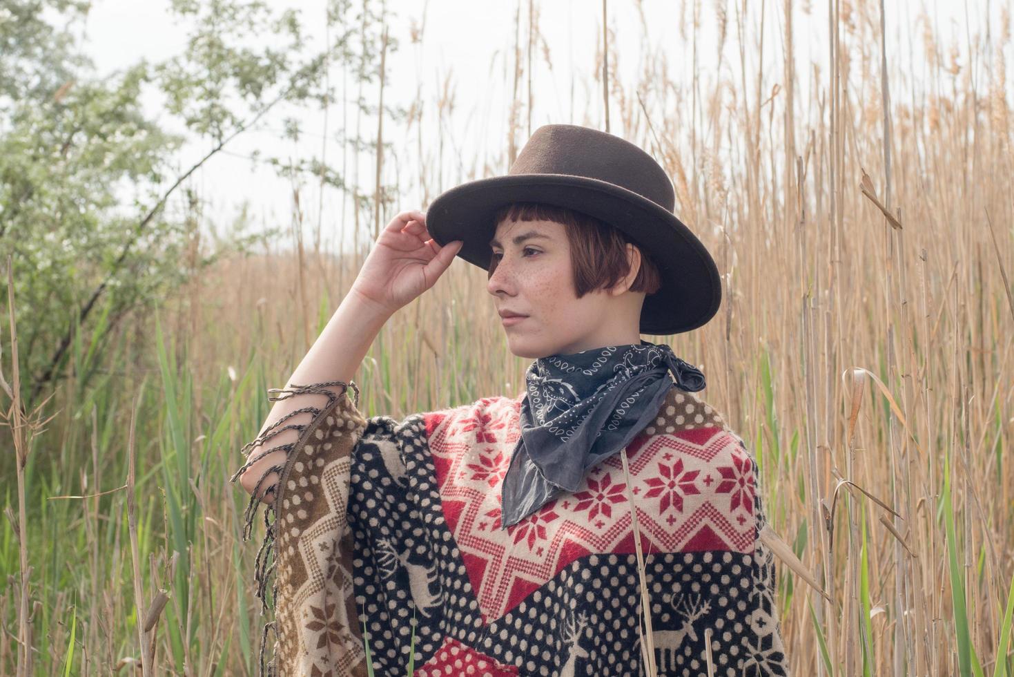 jeune femme voyageuse en poncho et chapeau marche dans les champs et ferme photo