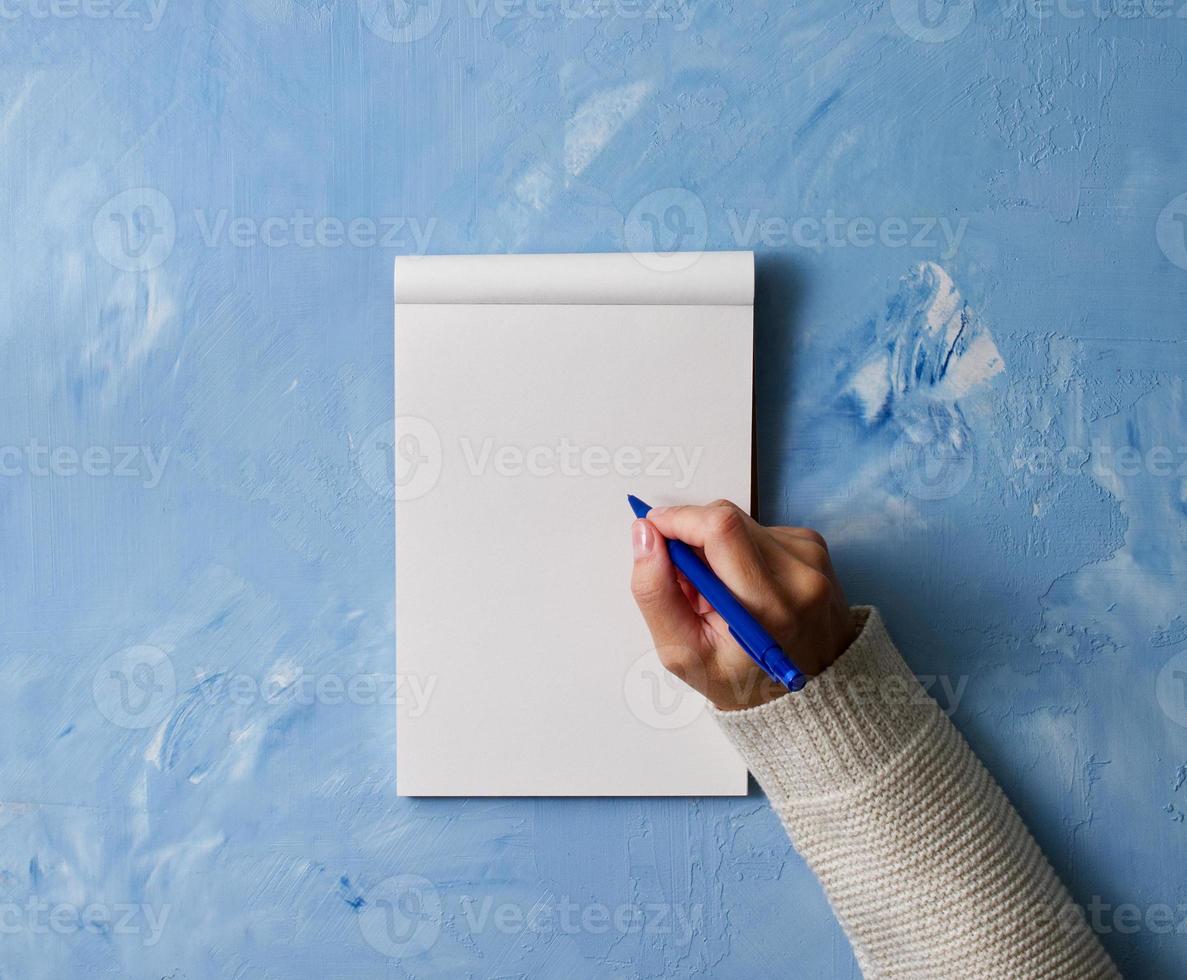 femme écrit dans un cahier sur une table en pierre bleue, main dans une chemise tenant un crayon, dessin de carnet de croquis, vue de dessus photo