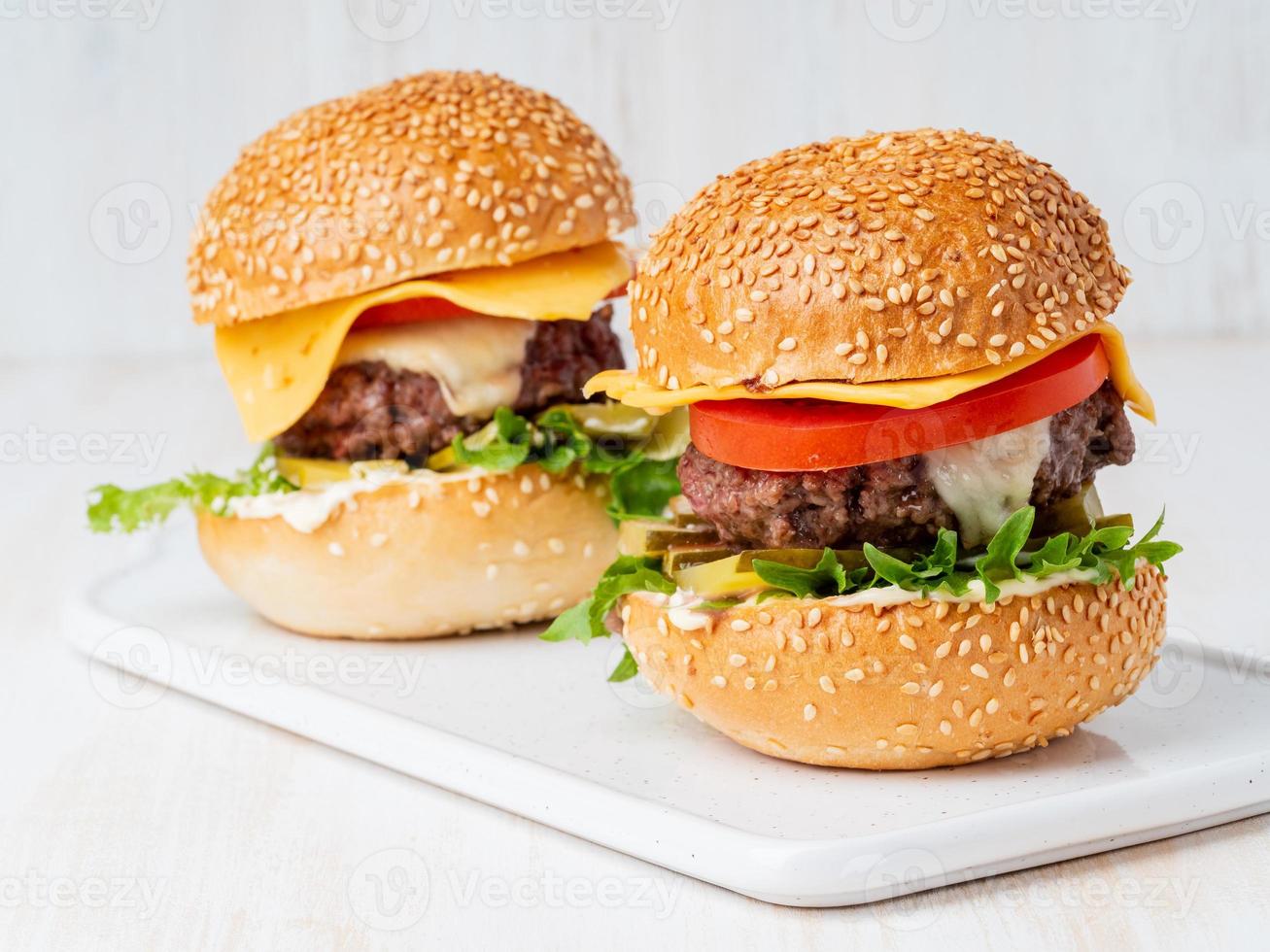 Deux hamburgers sur tableau blanc sur fond blanc, aliments gras malsains faits maison chauds photo