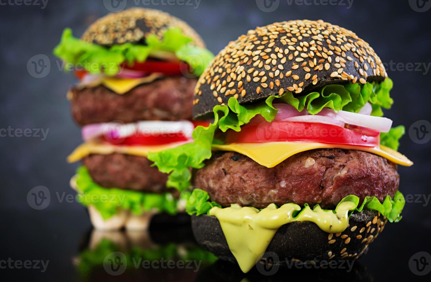 burger fait à la main sur fond sombre. délicieux burger noir photo