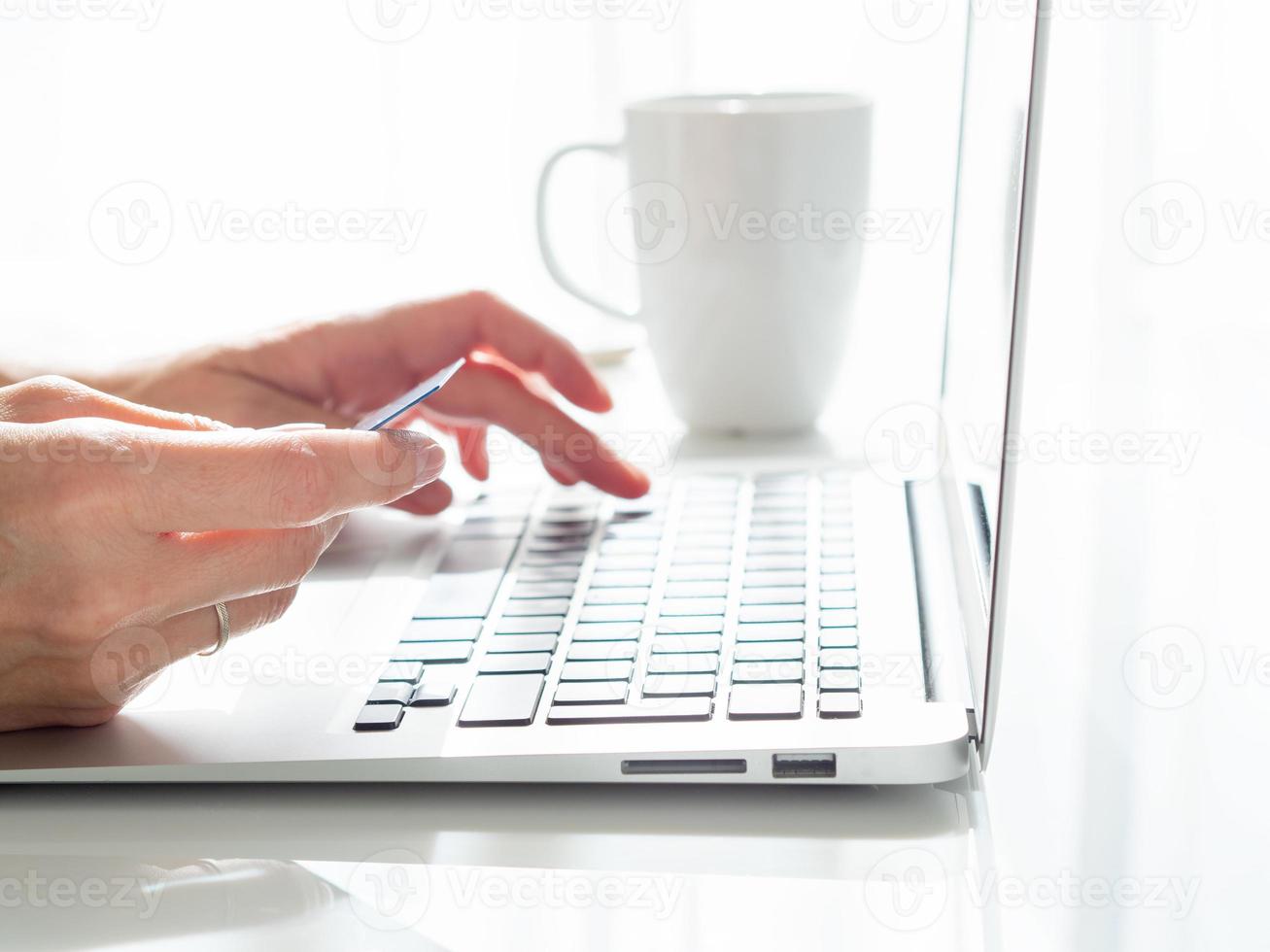 femme assise à une table, buvant du thé et regardant un ordinateur portable, payer ses achats photo