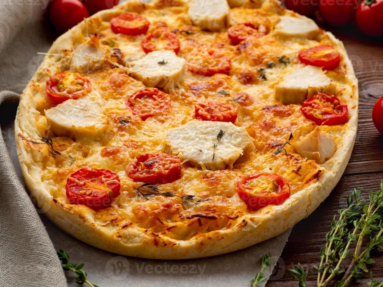 focaccia dorée appétissante aux tomates, viande de poulet, épices sur une table rustique en bois foncé photo