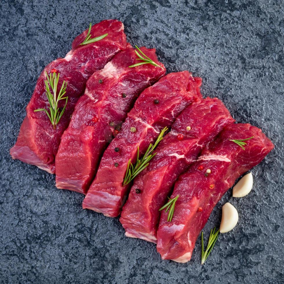 viande crue, steak de boeuf avec assaisonnement sur table en pierre noire, vue de dessus photo