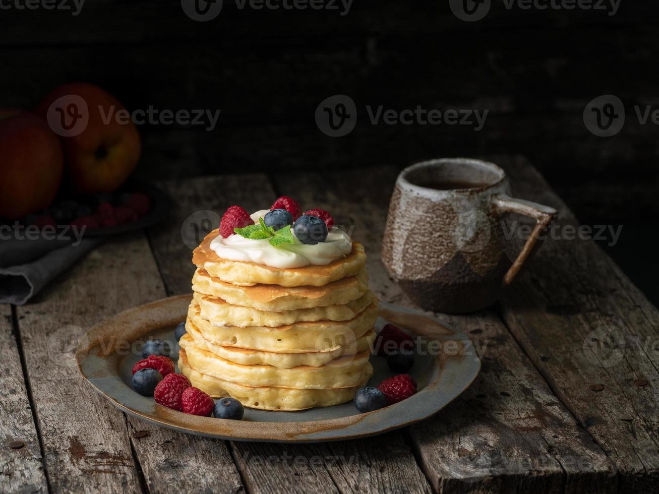 crêpe à la crème vanille, myrtilles et framboises. vieux fond en bois rustique de mauvaise humeur sombre. photo