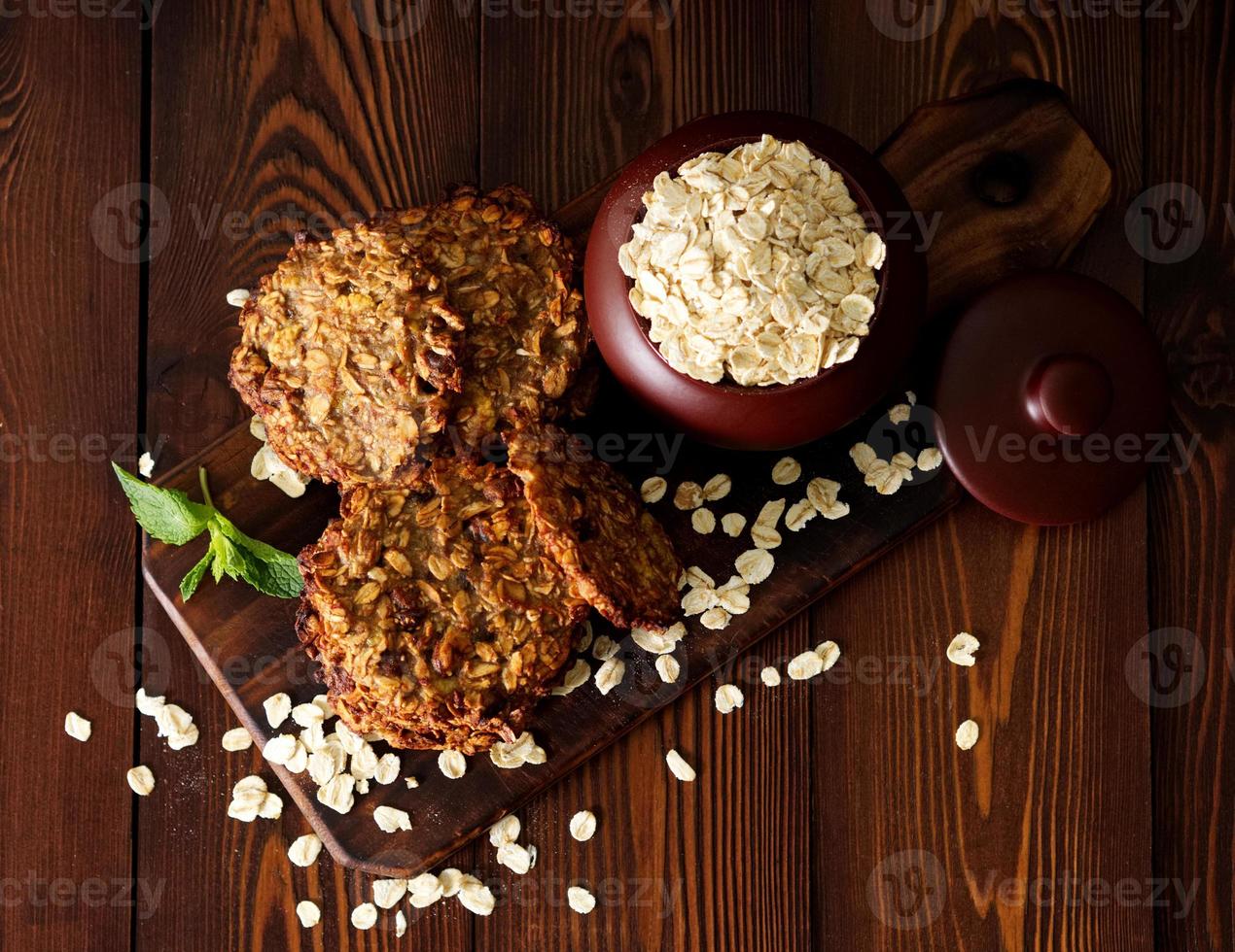 biscuits à l'avoine faits maison avec banane, avoine, noix, œufs et farine gratuits sur une table en bois brun foncé, vue de dessus. photo