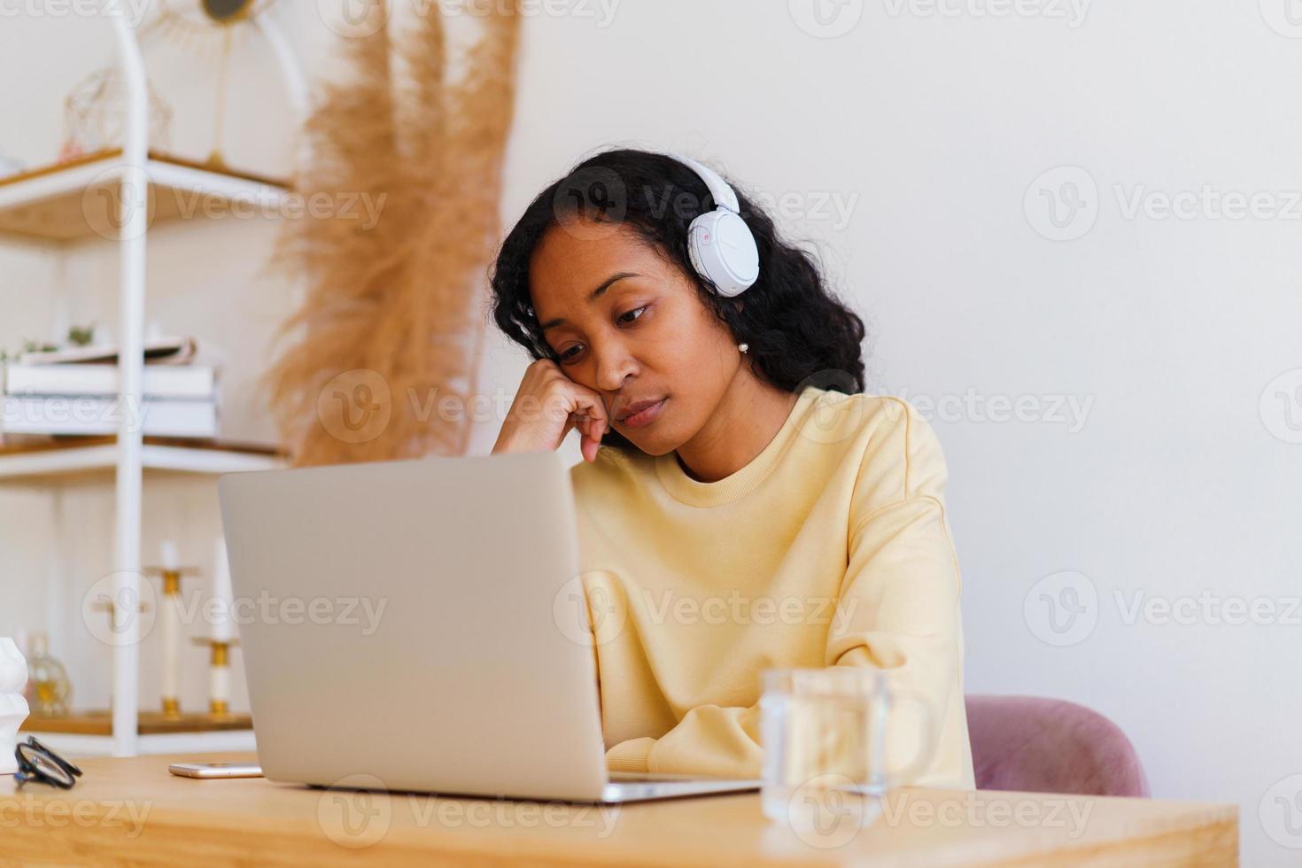 Étudiante afro-américaine ennuyée et fatiguée regardant un cours à distance en ligne sur un ordinateur portable photo