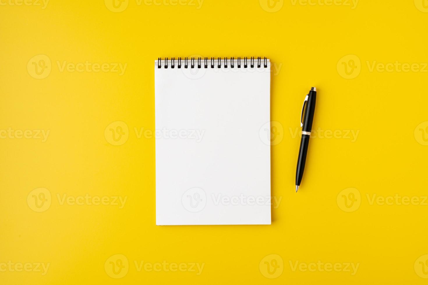 cahier à spirale vierge avec stylo plume sur fond jaune coloré, vue de dessus, espace pour copie photo