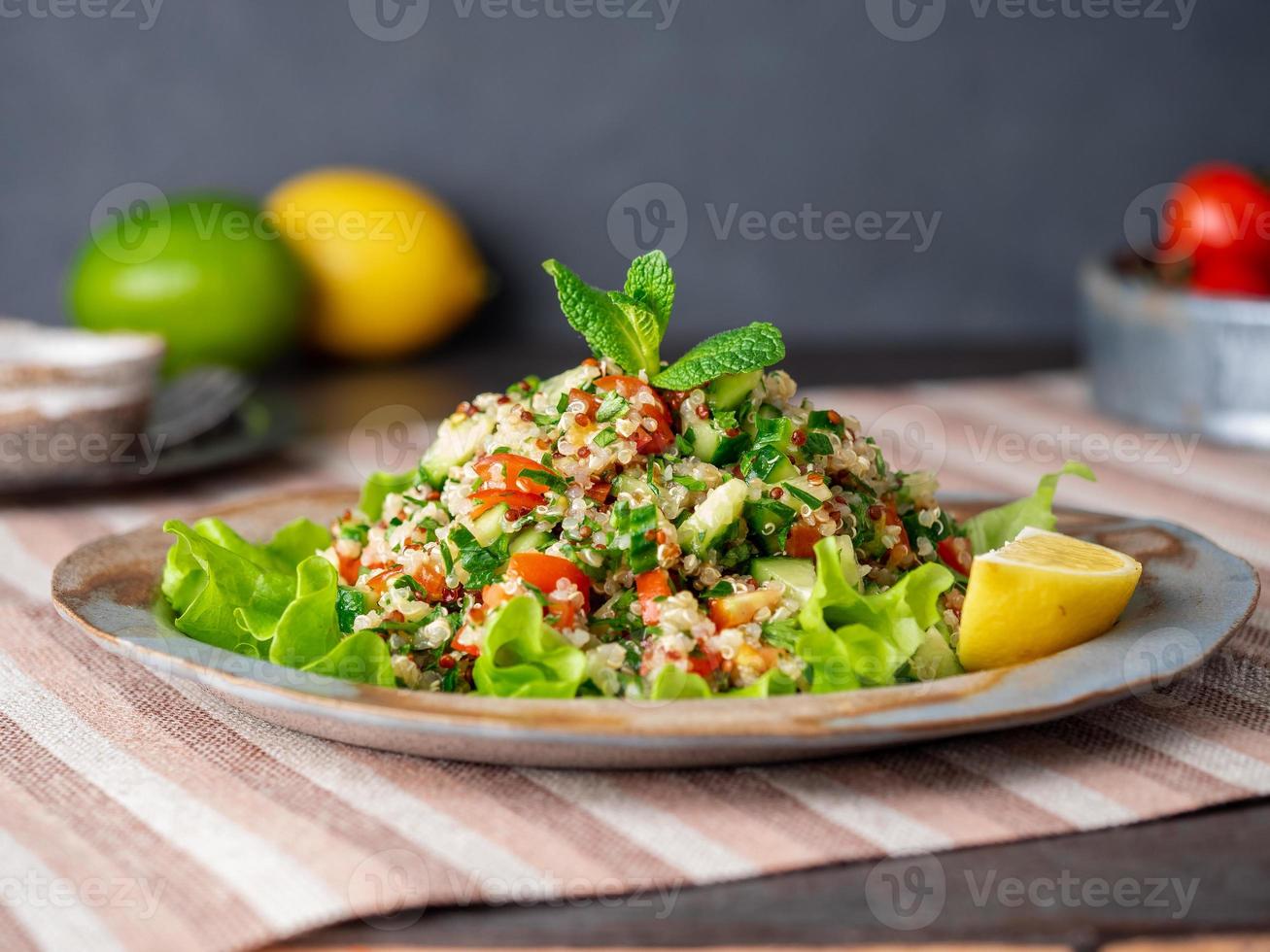 salade de taboulé au quinoa. cuisine orientale avec mélange de légumes, régime végétalien. vue de côté, serviette en lin, vieille assiette photo