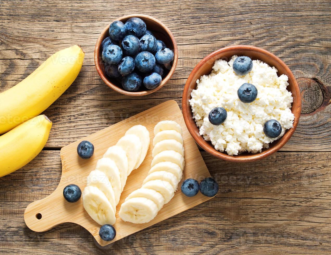 bol en bois brun de lait caillé fait maison avec banane, confiture, myrtilles photo