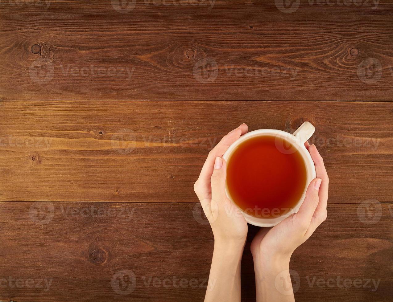 femme tenant une tasse de thé sur fond de bois foncé vue de dessus copie espace photo