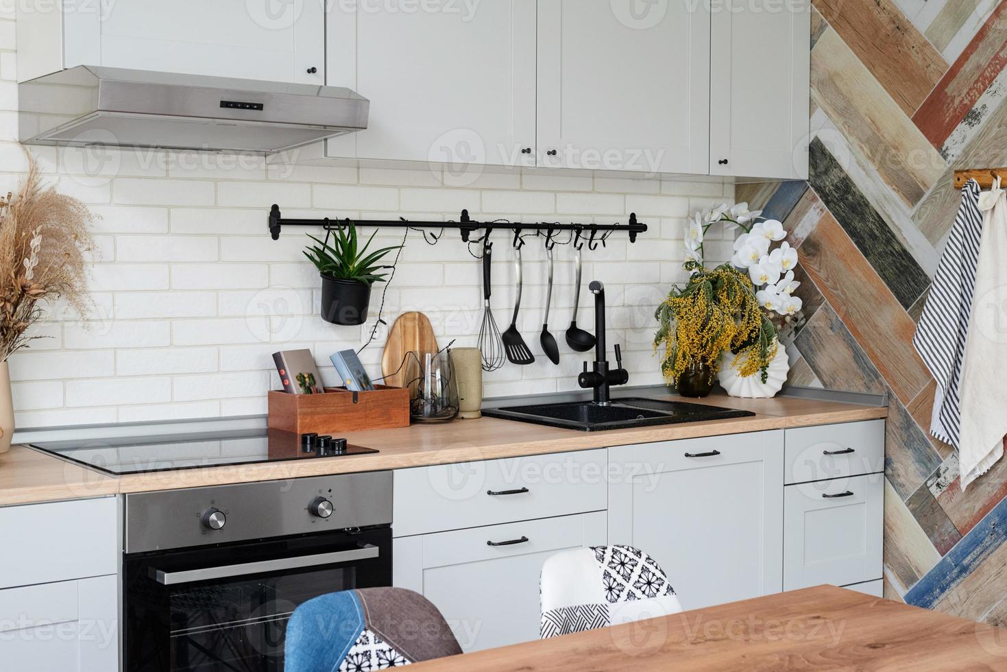 intérieur de cuisine de style rustique avec ustensiles de cuisine vintage et mur en bois. mobilier blanc et décor en bois dans un chalet lumineux à l'intérieur. photo