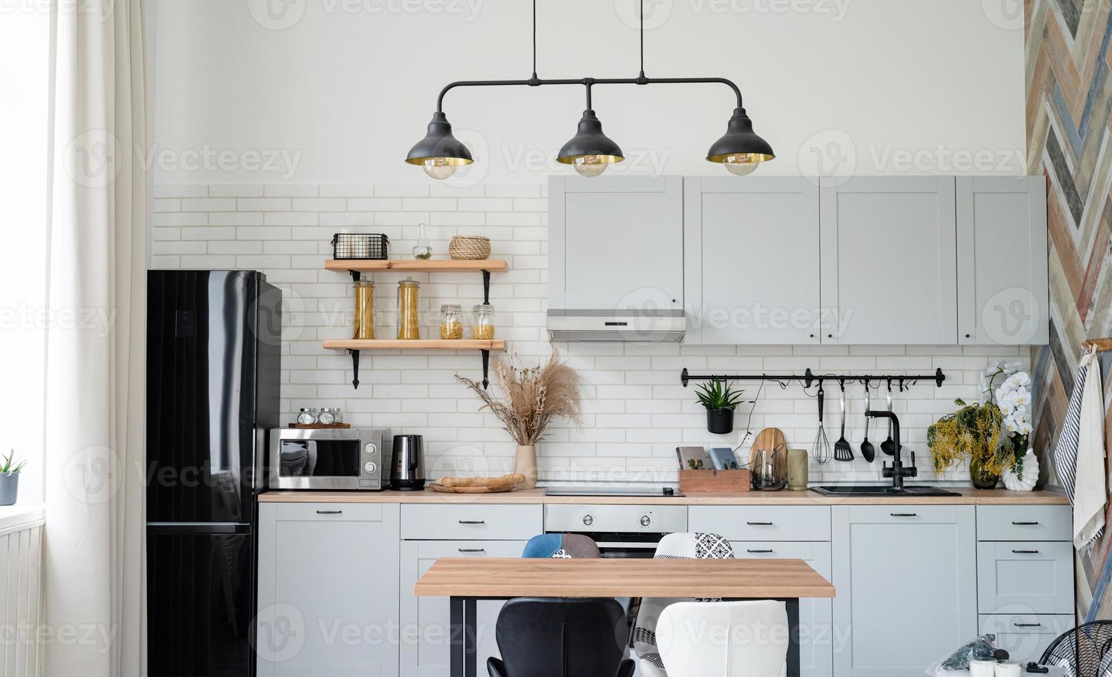 intérieur de cuisine de style rustique avec ustensiles de cuisine vintage et mur en bois. mobilier blanc et décor en bois dans un chalet lumineux à l'intérieur. photo