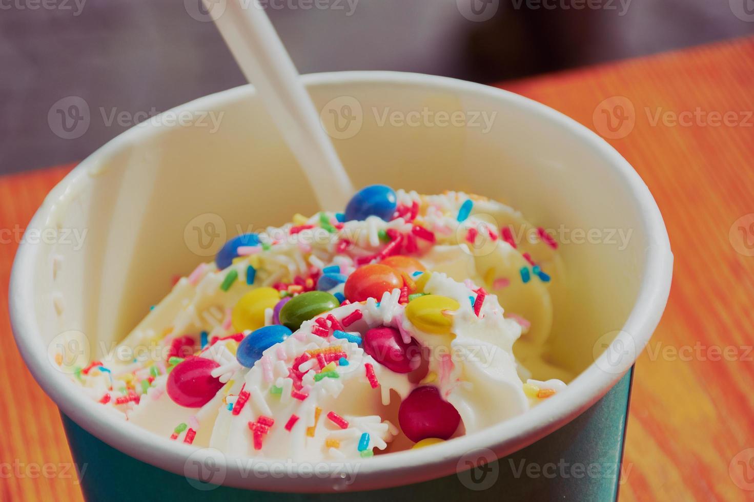 tasse avec de la glace au yaourt avec des garnitures sucrées comme des pépites multicolores photo