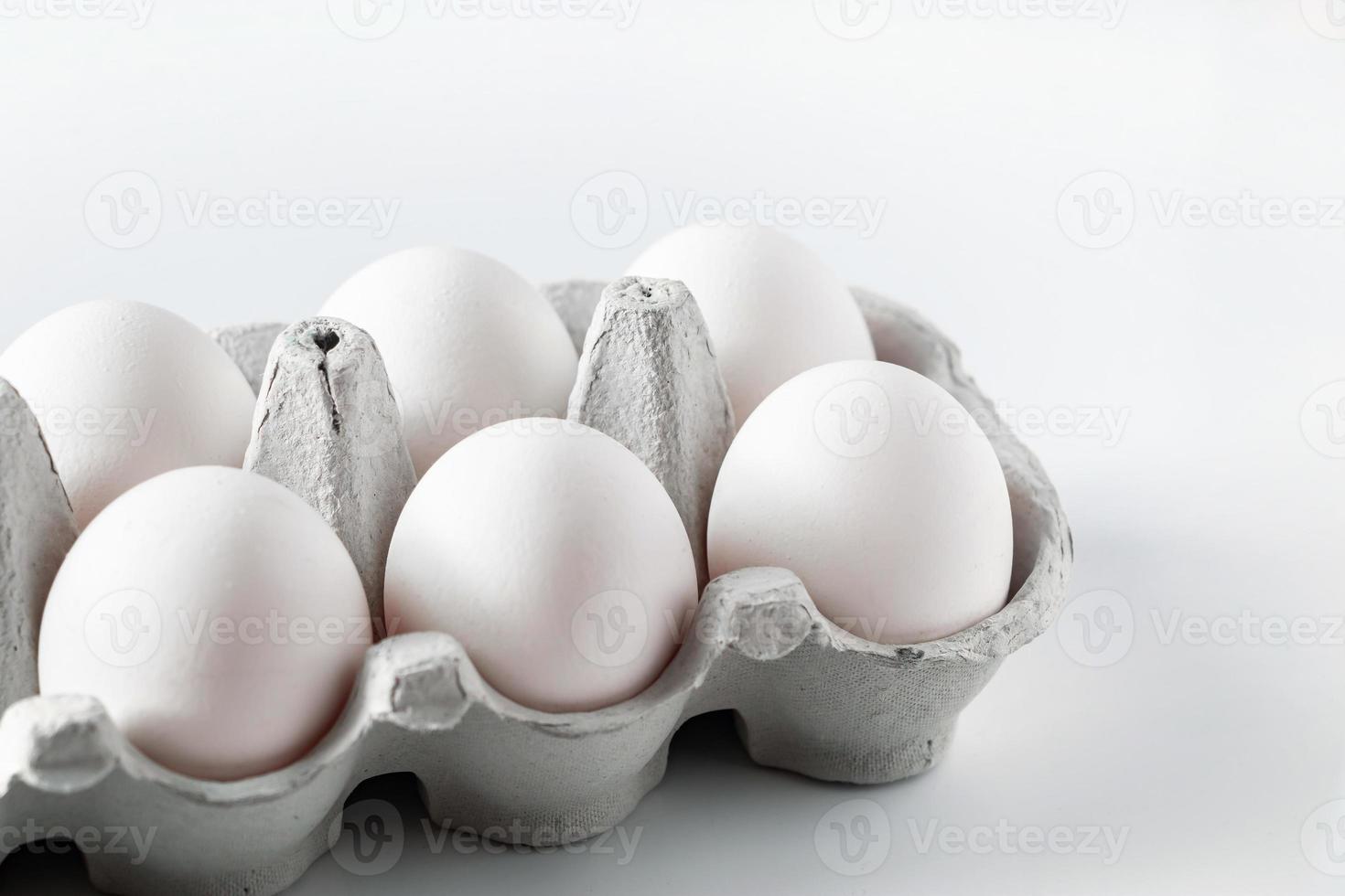 oeufs de poule blancs dans une boîte en carton sur fond clair photo