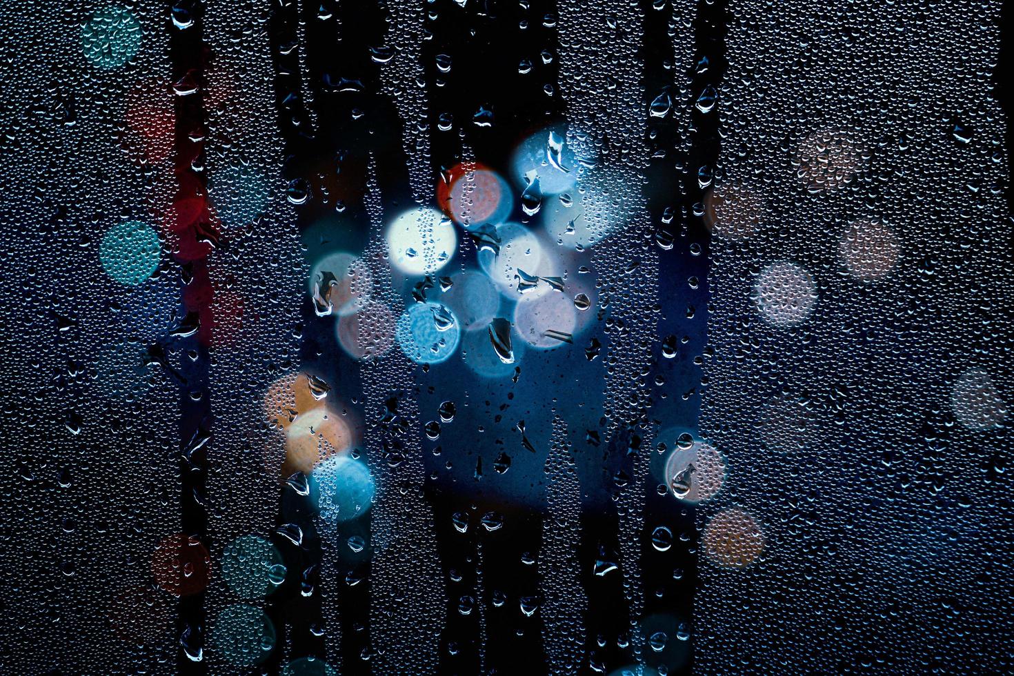 gouttes de pluie sur la fenêtre et les lampadaires la nuit photo