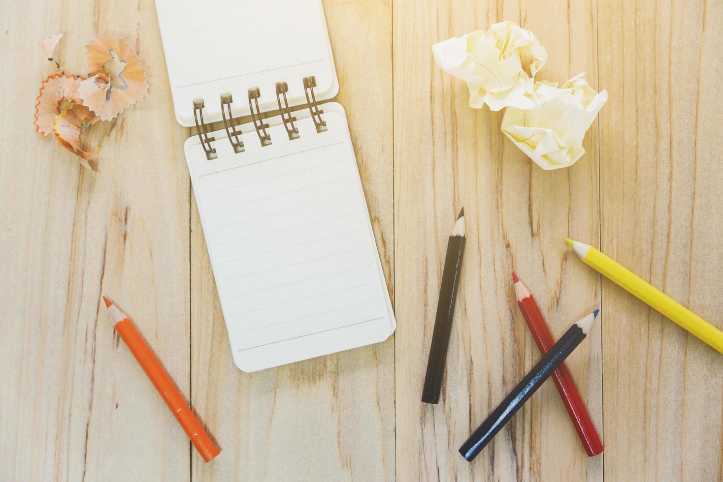 petit carnet de notes ou bloc-notes pour écrire des informations avec un crayon de couleur et des boules de papier froissées sur une table en bois. vue d'en-haut photo