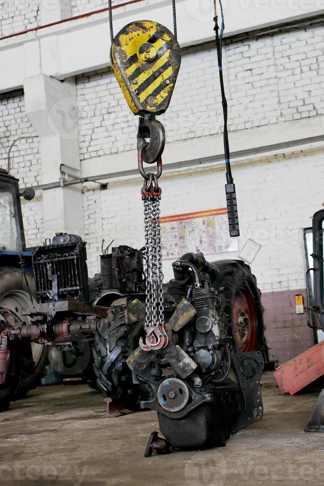 le moteur du tracteur est suspendu à un treuil photo