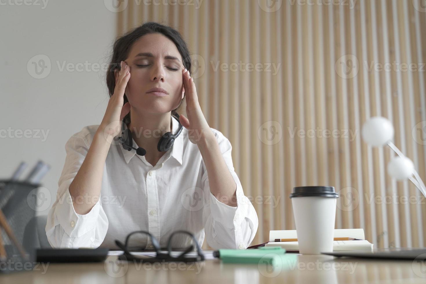 femme italienne frustrée aux yeux fermés massant les tempes, souffrant de maux de tête au travail photo