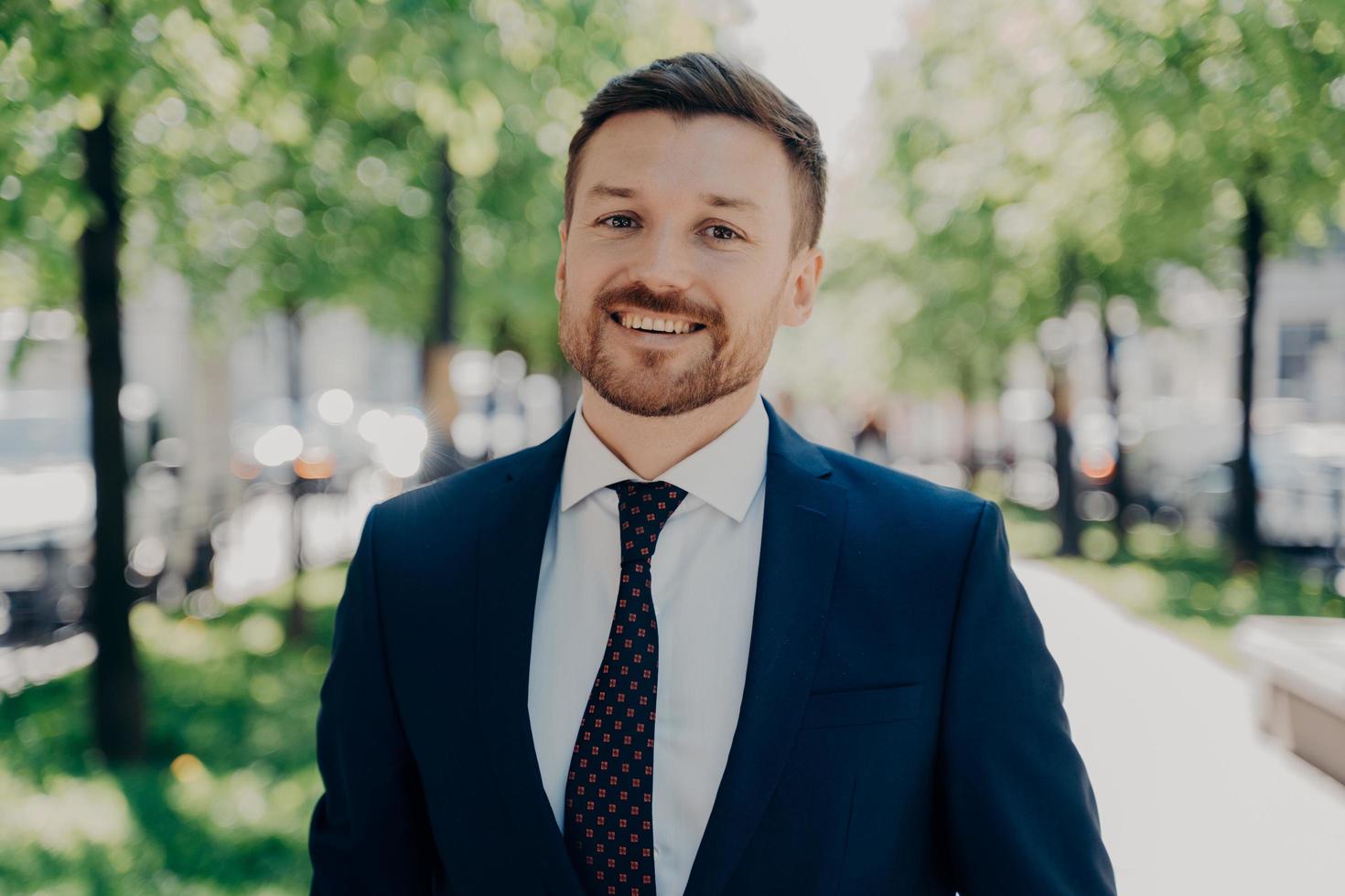 portrait rapproché d'un beau jeune homme d'affaires barbu souriant à l'extérieur photo